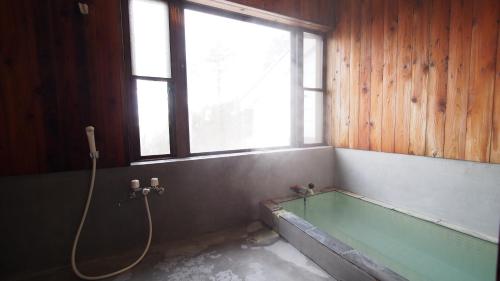 a bathroom with a bath tub with a window at Private hot-spring Villa in Kusatsu in Kusatsu