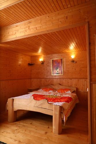 a bed in a wooden room in a cabin at Котедж у Карпатах in Tukholʼka