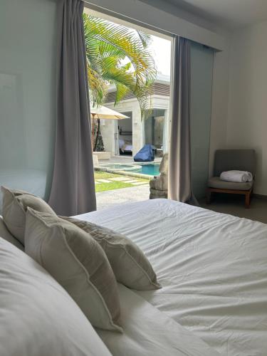 - un lit avec des draps et des oreillers blancs devant une fenêtre dans l'établissement Villa KMea 4, à Seminyak