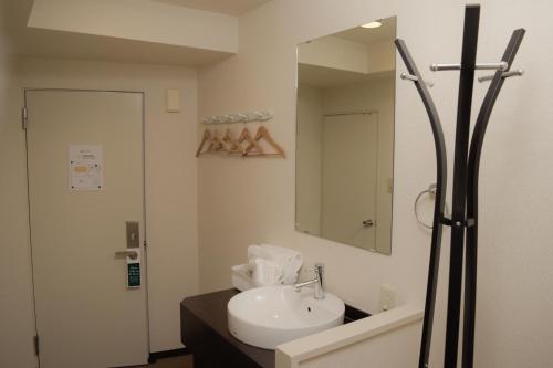 a bathroom with a sink and a mirror at HOTEL G-CUE 大阪谷町 in Osaka