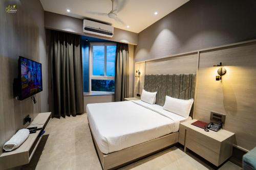 una camera da letto con un grande letto bianco e una televisione di Hotel Grand Central Park a Nānded