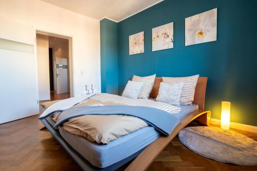 a large bed in a room with a blue wall at Doppelhaus- Villa Leipzig Schleußig , moderner Altbau Apartment Dachetage mit 2 Schlafzimmern und separatem Zusatzzimmer , Parkplatz - Balkon - Kamin - Eicheparkett - Arbeitsplatz in Leipzig