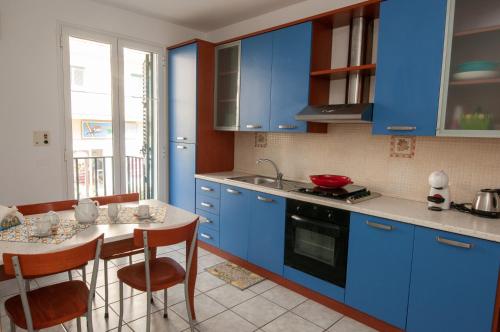 eine Küche mit blauen Schränken und einem Tisch mit Stühlen in der Unterkunft Lory's House - 400mt dal mare in Donnalucata