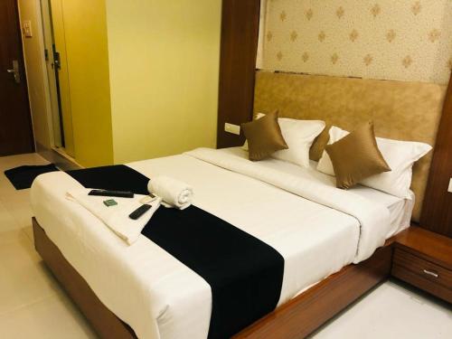 a bedroom with a large white bed with black and white sheets at 7even Hills- International Airport By Glitz Hotels in Mumbai
