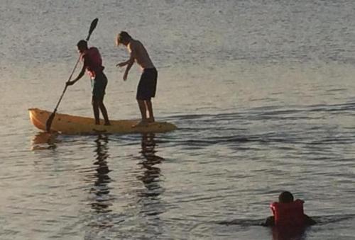 two men standing on a paddle board in the water at Lakeside Fish Farm in Bugesera