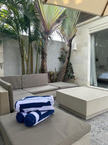 d'une terrasse avec un canapé et des palmiers avec des serviettes. dans l'établissement Villa KMea 4, à Seminyak