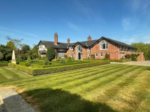 a large brick house with a large lawn at Fernside Annex in Pickmere