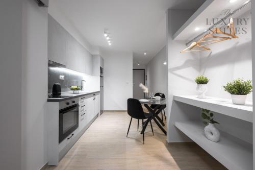 una cocina con encimeras blancas y una mesa con una silla en WeStay Apartments, The Luxury Suites en Tesalónica