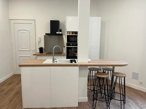 una cocina con armarios blancos y una barra con taburetes en T2 rénové - 2/4 p. Wi-Fi / Netflix, en Toulouse