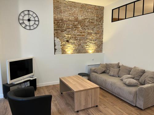 sala de estar con sofá y reloj en la pared en T2 rénové - 2/4 p. Wi-Fi / Netflix, en Toulouse