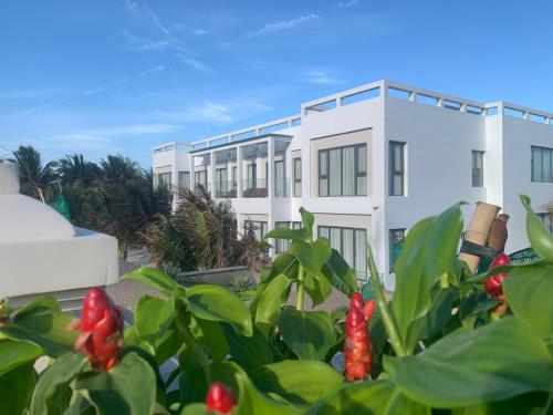 a white building with red flowers in front of it at Bờ Biển Vàng Hotel in Ke Ga