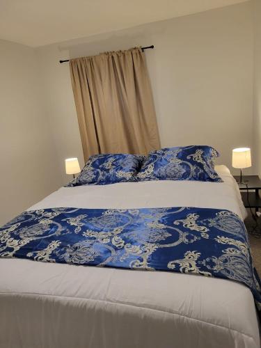 Una cama con una manta azul y blanca. en Furnished rooms close to U of A in Edmonton, en Edmonton