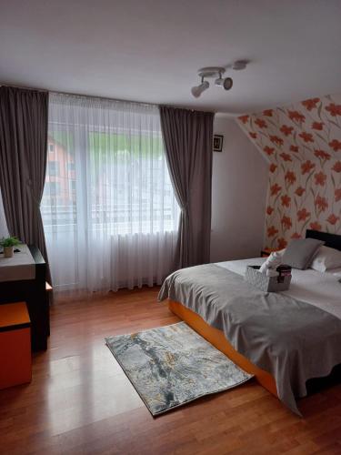 a bedroom with a bed and a large window at VILA SIMONA in Moieciu de Sus