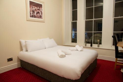 uma grande cama branca num quarto com janelas em The Knighton Hotel - Full House em Knighton