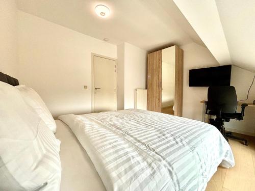 a white bedroom with a bed and a desk at Il Casolare in Beersel