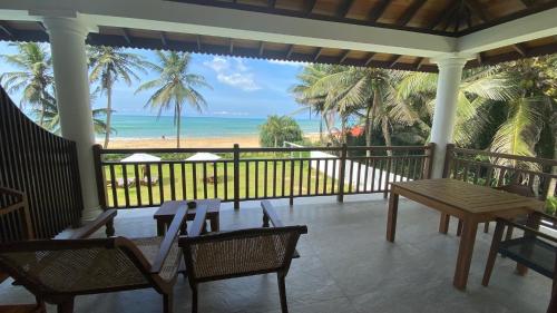 a porch with a table and chairs and the beach at Sea Star Boutique Hotel in Hikkaduwa
