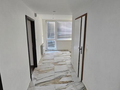 um corredor vazio com piso em azulejo e uma janela em MINOS em Košice