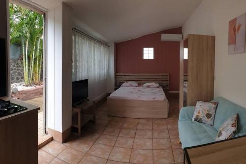 ein Schlafzimmer mit einem Bett, einem Sofa und einem TV in der Unterkunft Ti Caz Emma in La Possession