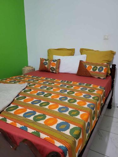a bed with a colorful comforter and pillows on it at LE COROSSOL APPART in Mamoudzou