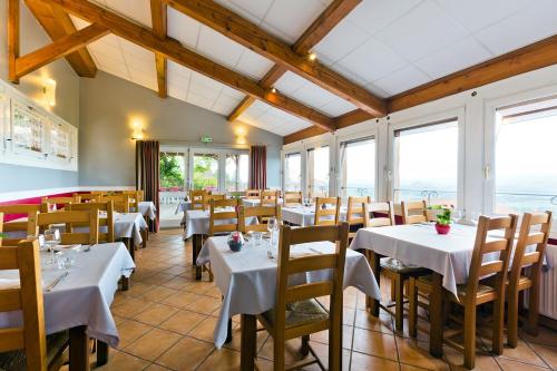 a restaurant with white tables and chairs and windows at Auberge De Margot in Usson