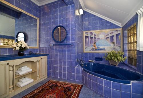 baño de azulejos azules con bañera y lavamanos en Royal Ridge Guesthouse en Pretoria