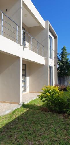 a white house with a balcony and a yard at ANILLAH APPARTMENTS in Centre de Flacq