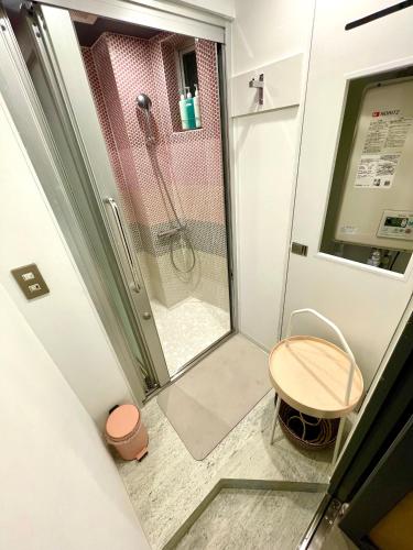 a bathroom with a shower with a table and a stool at Andon Ryokan in Tokyo