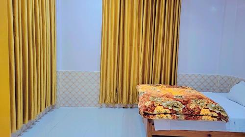 a room with two beds and a window with yellow curtains at Hotel Miandam Palace in Mingora