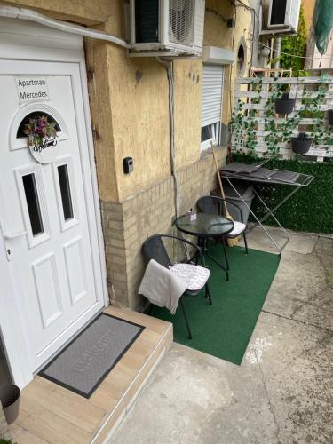 patio z białymi drzwiami, krzesłami i stołem w obiekcie Apartman Mercedes w Segedynie