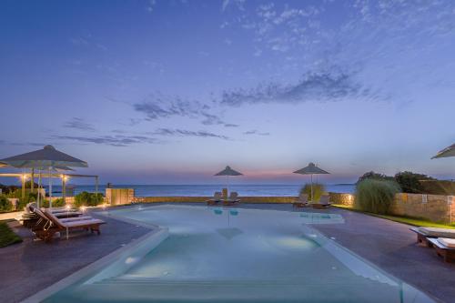 a swimming pool with a view of the ocean at night at Callisto Seaside Homes & Suites in Marathopolis