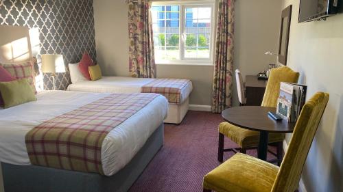 a hotel room with two beds and a table at Stone House Hotel ‘A Bespoke Hotel’ in Stone