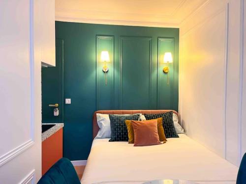 une chambre avec des murs verts et un lit avec des oreillers dans l'établissement Studio Romantique Paris Moulin Rouge Montmartre, à Paris