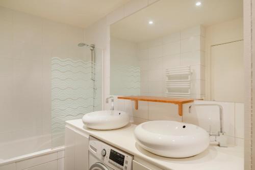une salle de bain blanche avec deux lavabos et une douche dans l'établissement Paris Arsonval Design Residence, à Paris