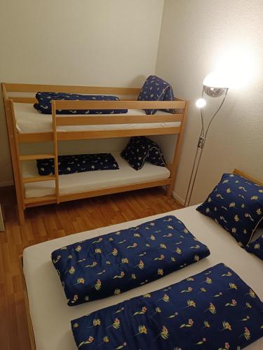 Apartment Jolie في إنترلاكن: غرفة بسريرين بها شراشف زرقاء ومصباح