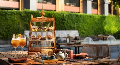 a table with a bird cage filled with pastries and drinks at Avista Grande Phuket Karon - MGallery in Karon Beach