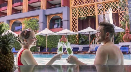 a man and a woman holding champagne glasses near a swimming pool at Avista Grande Phuket Karon - MGallery in Karon Beach