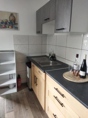 - une cuisine avec un évier et un comptoir avec des bouteilles de vin dans l'établissement La Petite Goulette, à Commes