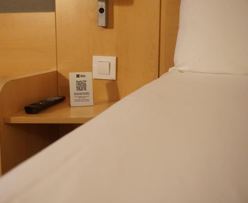 a bed with a remote control on a wooden shelf at Ibis Girona in Girona