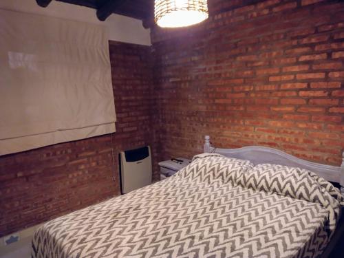 a bedroom with a bed and a brick wall at La Casita in Neuquén