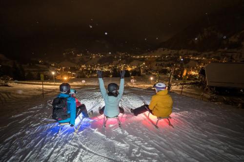 three people sitting in the snow at night at Sunshine @ Rosie Design Chalet in Bad Kleinkirchheim