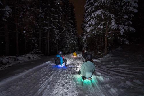 two people are sitting in the snow at night at Sunshine @ Rosie Design Chalet in Bad Kleinkirchheim