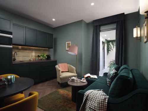 a living room with a green couch and a table at The Other House South Kensington in London
