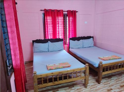 2 Betten in einem Zimmer mit rosa Vorhängen in der Unterkunft Quality Inn Varkala in Varkala