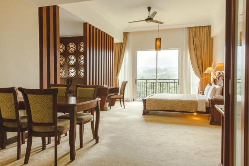 a hotel room with a bed and a table and chairs at Heritage Hotel Cameron Highlands in Cameron Highlands