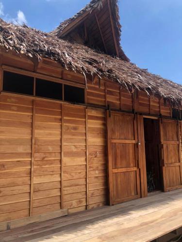 a wooden building with two doors and a thatch roof at The Tropical Koh Mook in Koh Mook