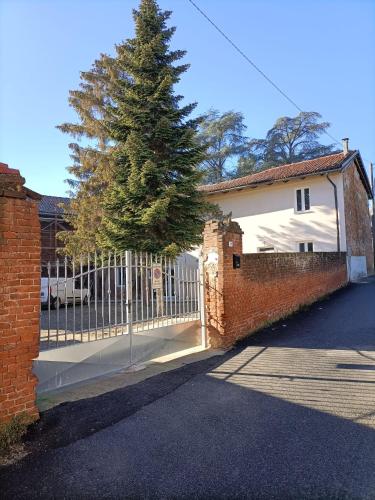 a fence with a tree in front of a house at La dimora del capitano in Quattordio