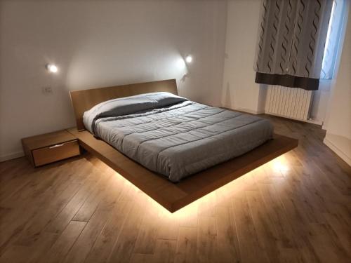 uma cama num quarto com piso em madeira em La dimora del capitano em Quattordio