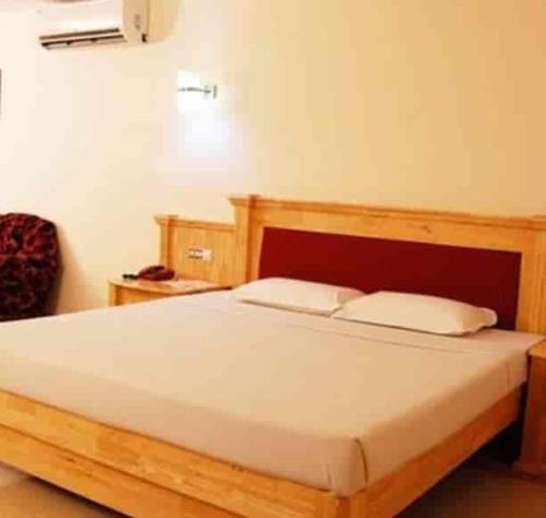 1 dormitorio con 1 cama de madera y 2 almohadas en HOTEL SKY PARK, en Mattanūr