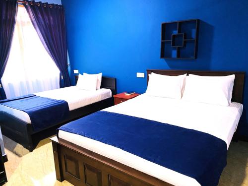 a bedroom with two beds and a blue wall at Nilaveli Hybrid Holiday Hotel in Nilaveli