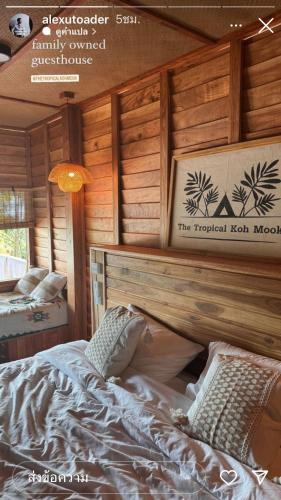 a bedroom with a bed in a log cabin at The Tropical Koh Mook in Koh Mook